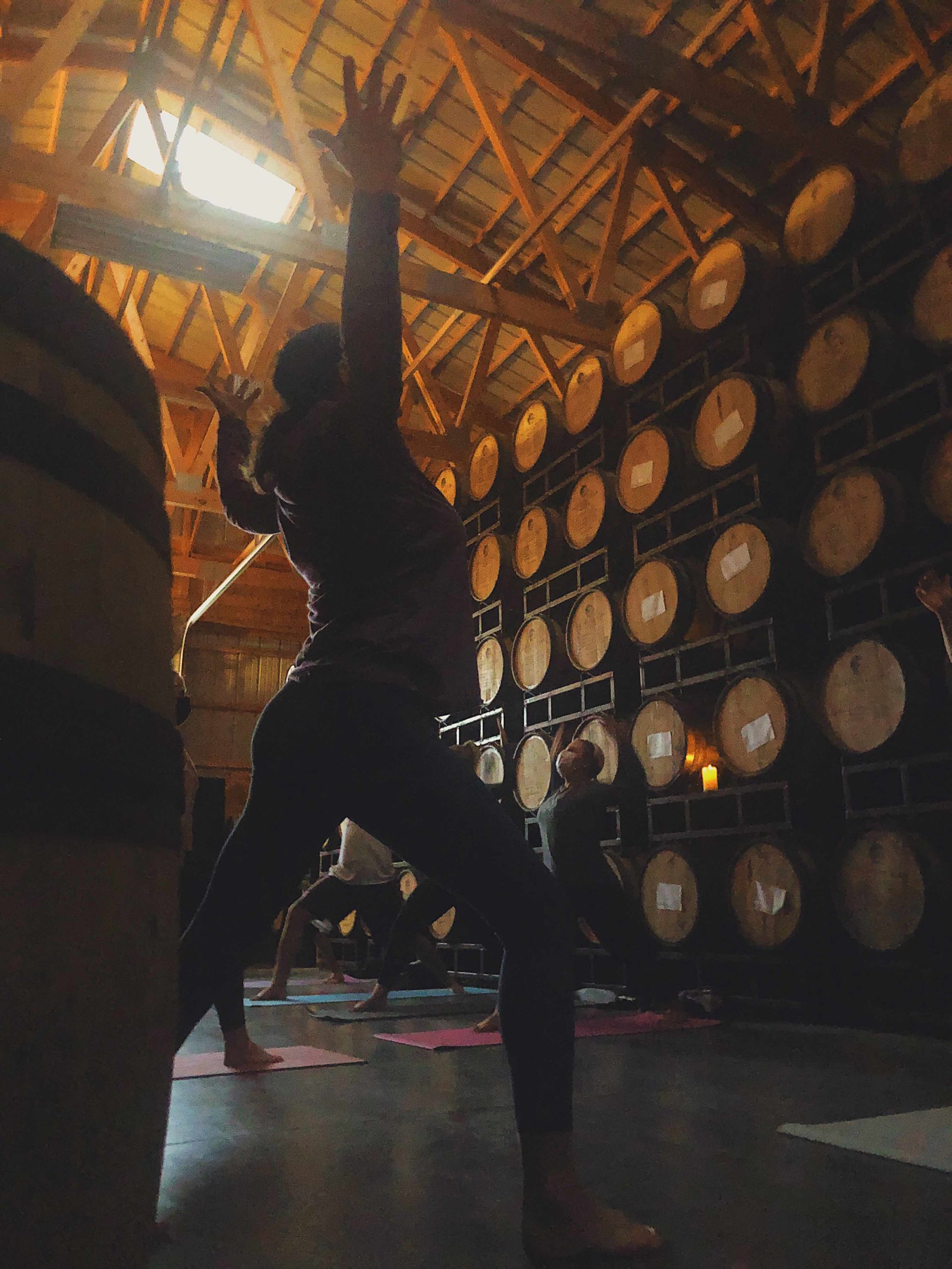 Yoga & Whiskey participants stretch and relax during in the rackhouse, surrounded by barrels of whiskey