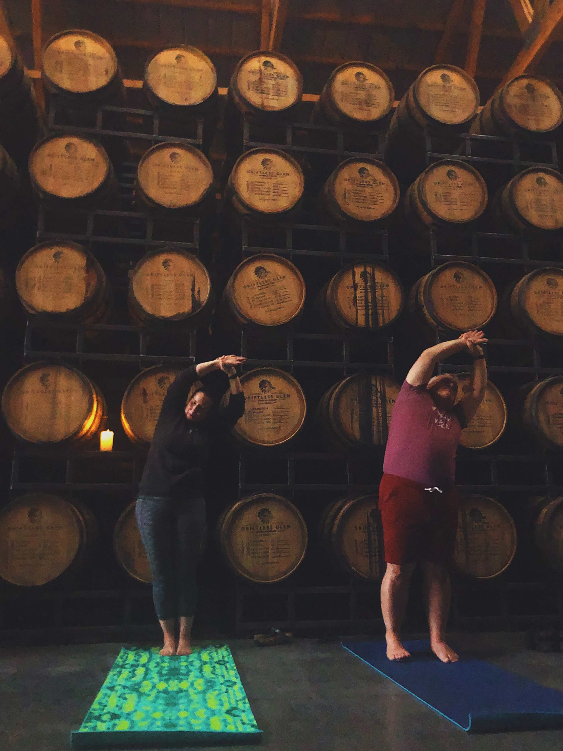 Yoga & Whiskey participants stretch and relax during in the rackhouse, surrounded by barrels of whiskey