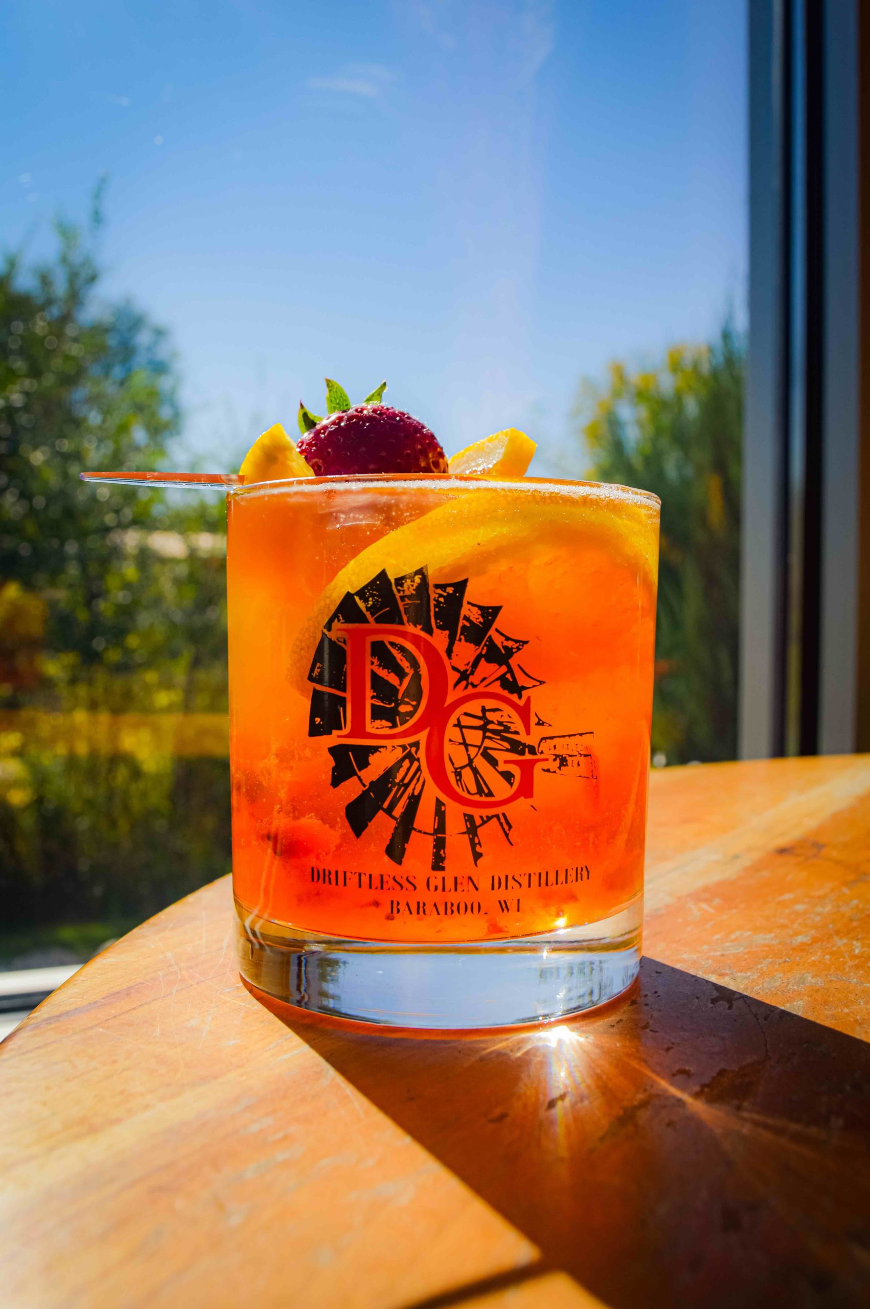 Strawberry Peach Old Fashioned in a glass sitting in front of a window with sunshine